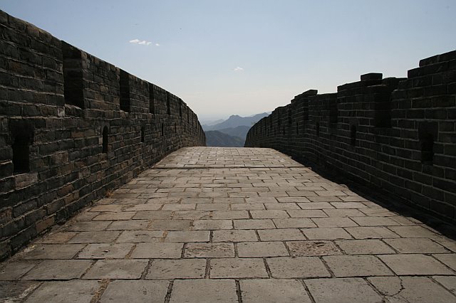 Ancient stone pathway on the Great Wall of China with scenic mountain views in the background.