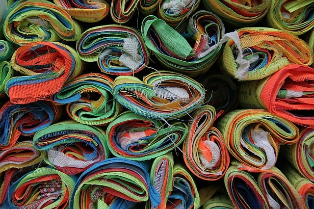 Colorful rolled-up fabric straps stacked together, showcasing vibrant patterns and textures.