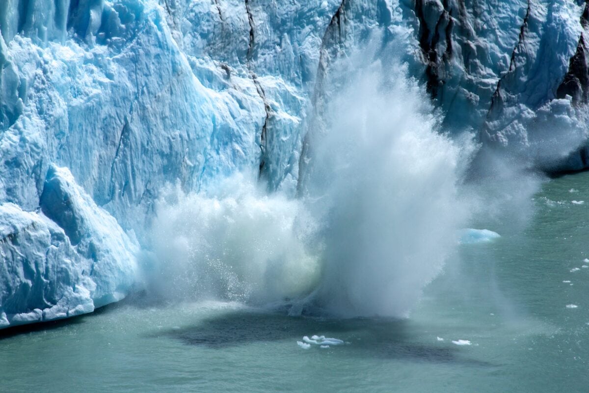 Ice calving from a glacier into the ocean creates a splash and waves, showcasing the stunning natural beauty of Argentina's glaciers.