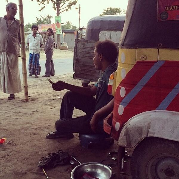 Indian mechanic eats ice cream as he repairs Rickshaw