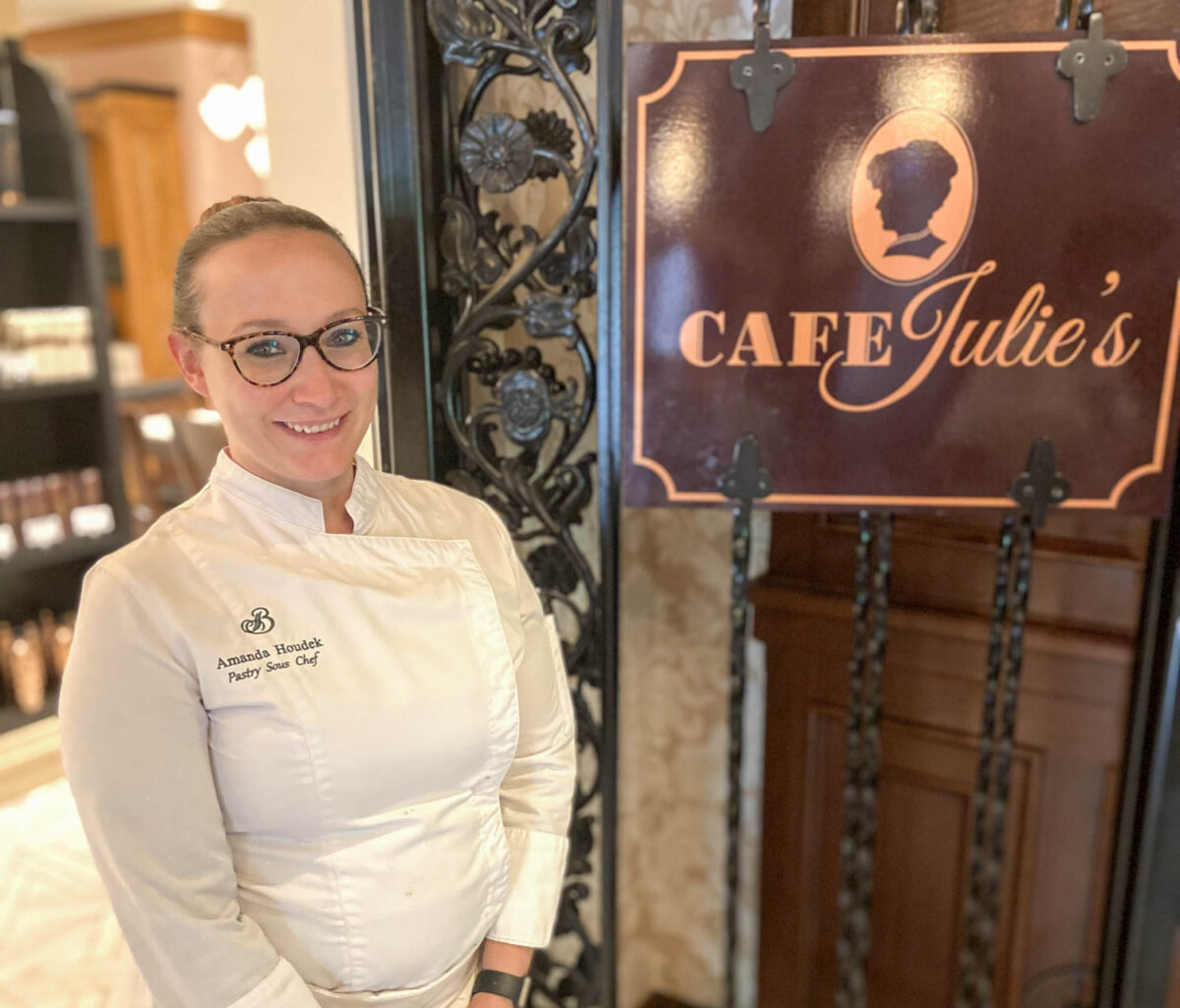 Pastry Chef at Broadmoor standing near sign for Cafe Julie's